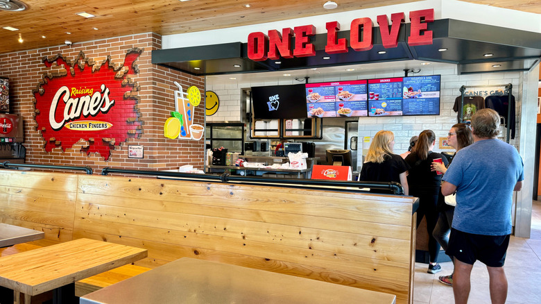 People stand in line at a Raising Cane's register.