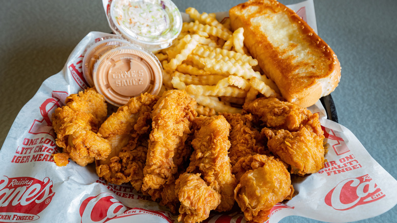 Basket of Raising Cane's chicken fingers, fries, toast, slaw, and dipping sauce