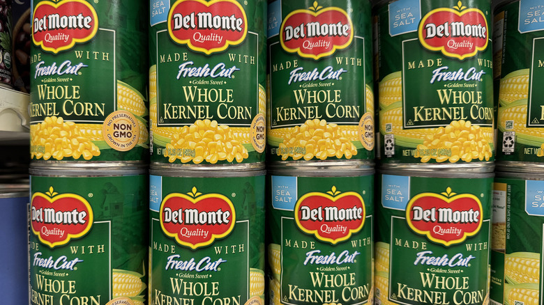 Cans of corn on a store shelf.