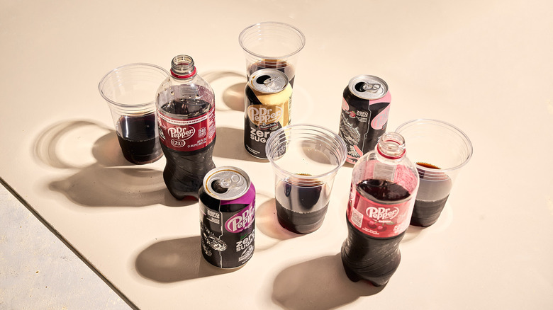 Bottles and cans of Dr. Pepper on a table, with with plastic cups