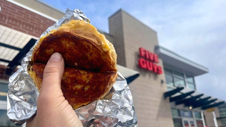 Hand holding Five Guys' Grilled Cheese in front of store