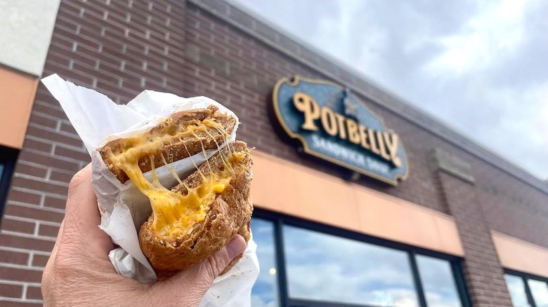 Hand holding Potbelly Sandwich Works' Grilled Cheese in front of store