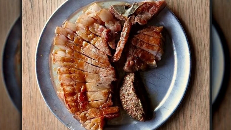 A sliced Berkshire pork chop served on a sliver plate from Pizza East in London