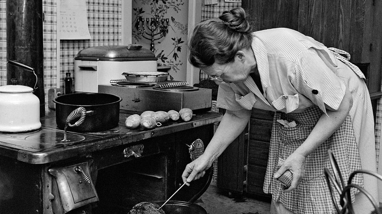black and white photo of old woman cooking