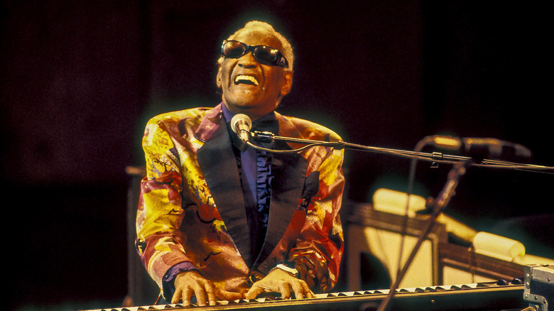 Singer Ray Charles playing the piano and singing into a microphone