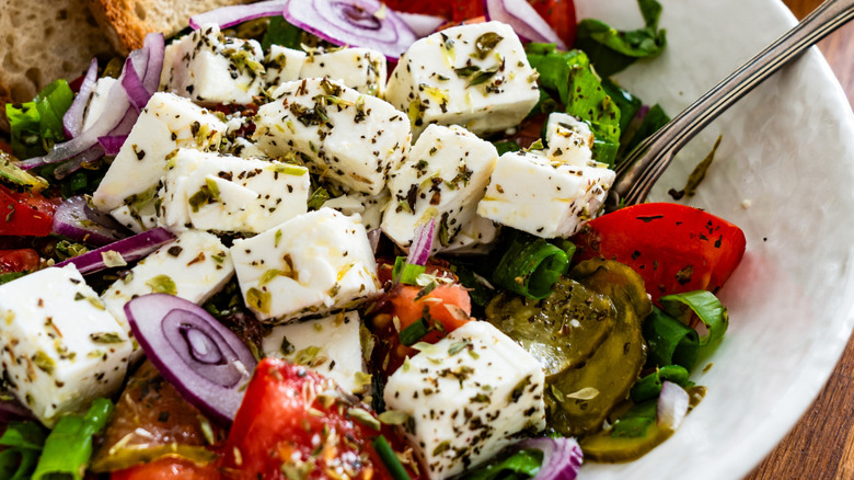 Greek style salad in a bowl with tomatoes, feta cheese, and dill pickles