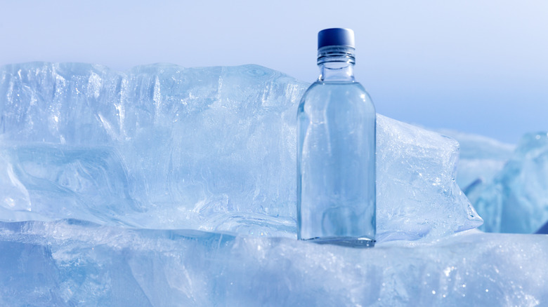 A glass bottle next to block ice
