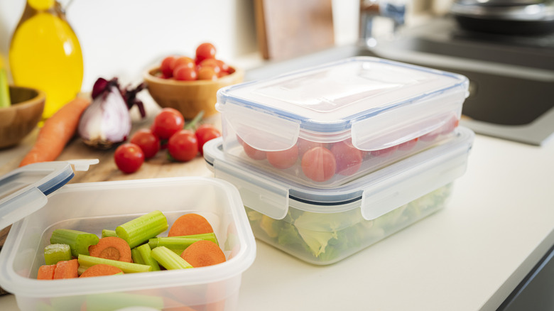 Plastic food containers filled with vegetables.