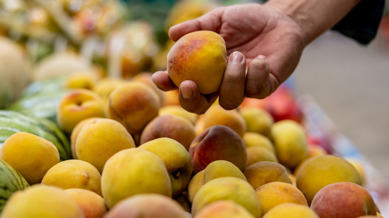 Person choosing peach at market