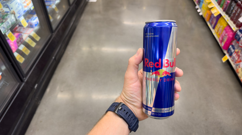 Redbull energy drink in hand in a supermarket.