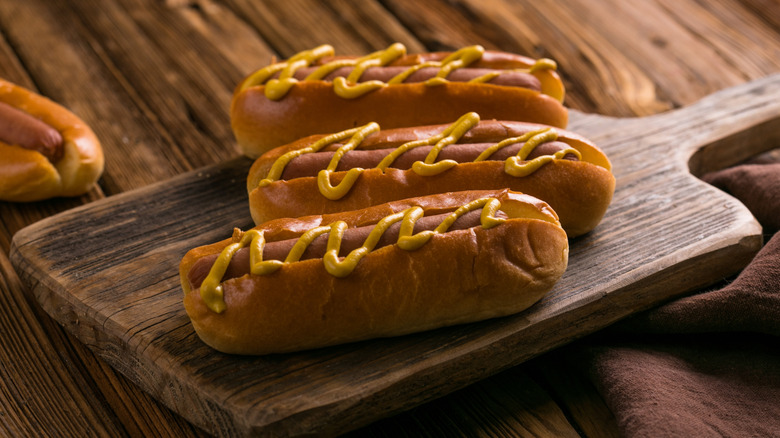 Hot dogs with mustard on a wooden cutting board