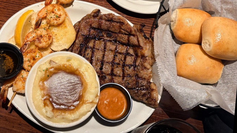 Steak, mashed potatoes, shrimp, and rolls on table at Texas Roadhouse