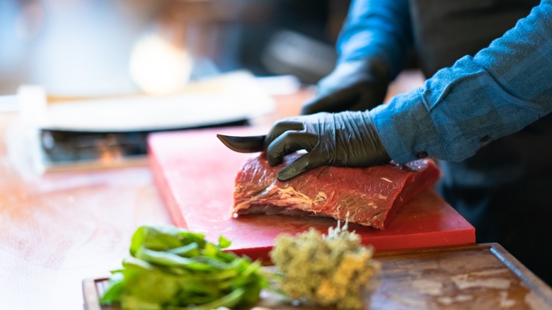 a slab of beef being hand-cut into steaks