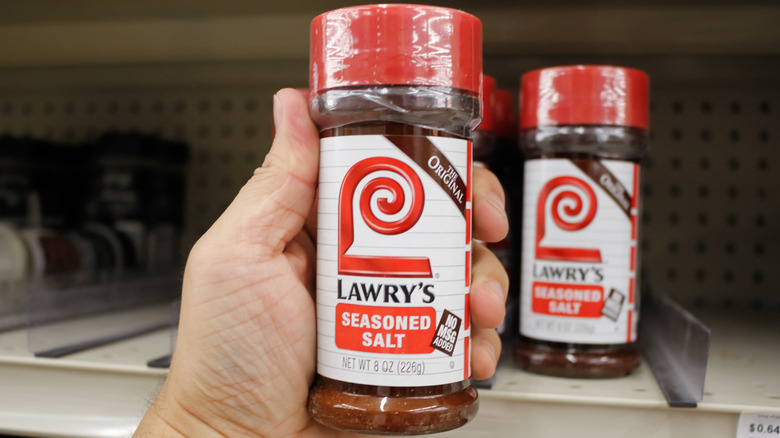 Person's hand holding a container of Lawry's Seasoned Salt at the grocery store