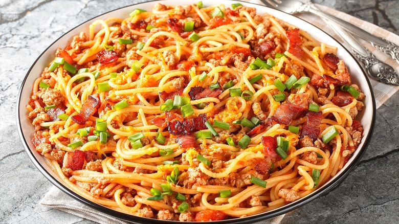 Large plate of cowboy spaghetti with chopped bacon and green onions