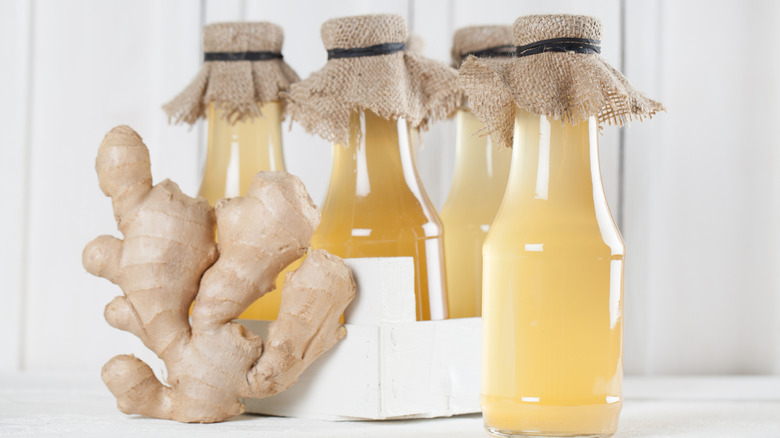 bottles of homemade ginger syrup with a piece of ginger.
