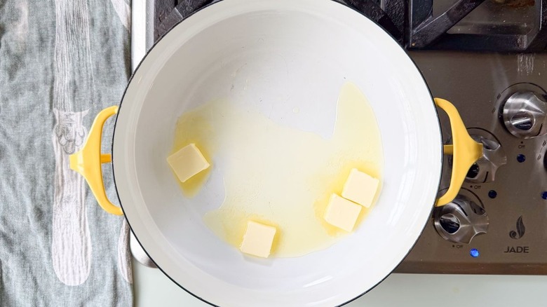Butter pats melting in yellow Dutch oven on stovetop