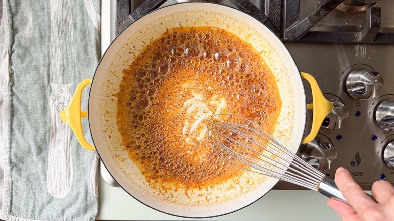 Whisking miso paste and smoked paprika into brown butter in Dutch oven on stovetop