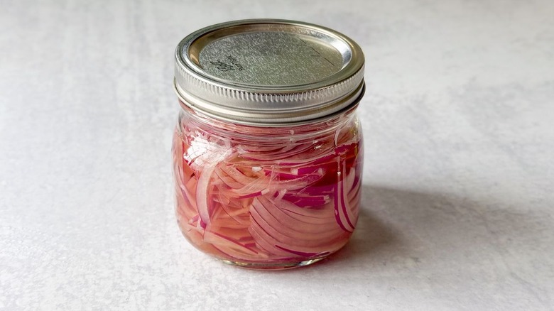 Pickled red onion slices in glass jar