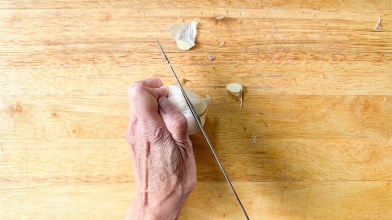 Slicing head of garlic horizontally on cutting board