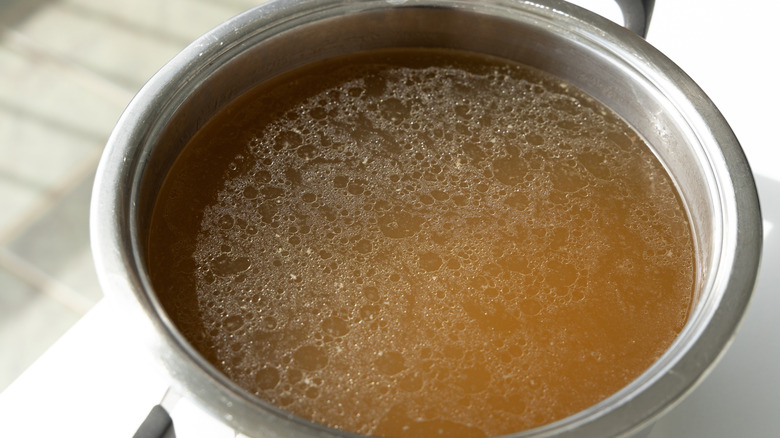 A pot of broth with fat floating on top
