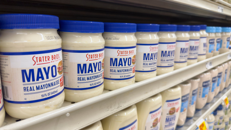 Jars of mayo lined up on a supermarket shelf.