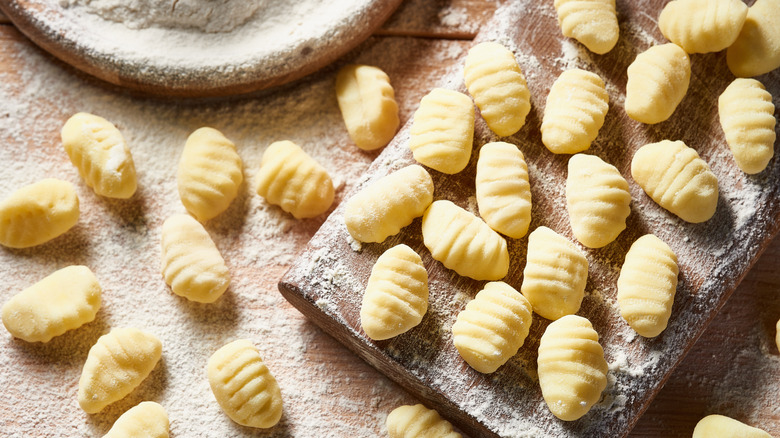 A flour-dusted tabletop covered with uncooked gnocchi