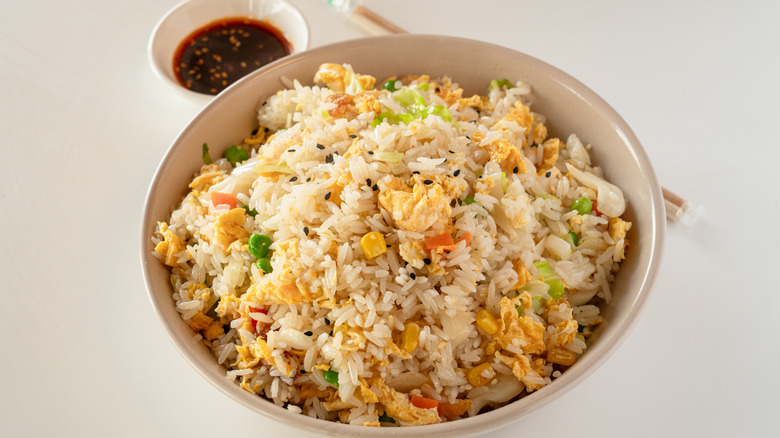 A bowl of fried rice set against an off-white background.
