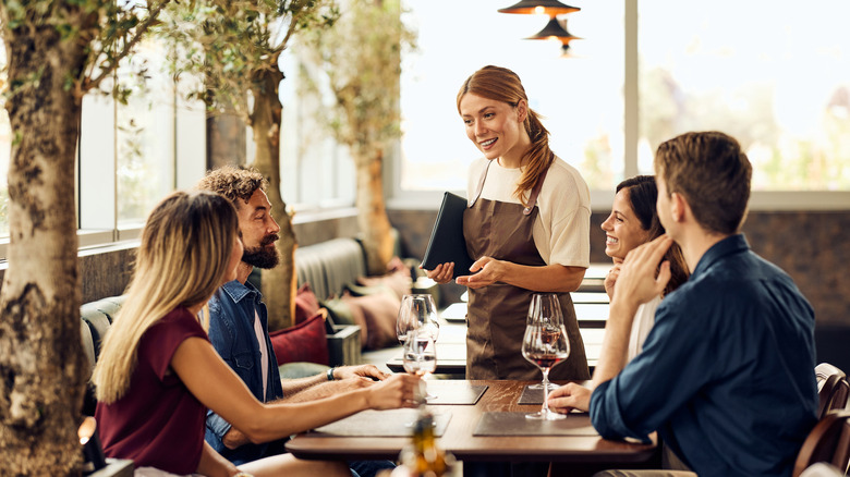 Table of four ordering from a waitress at a restaurant