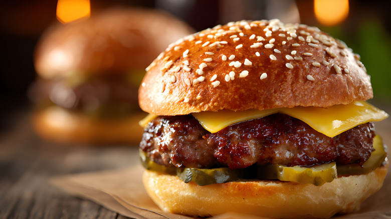 Cheeseburger with pickles and cheese inside a sesame seed bun, closeup