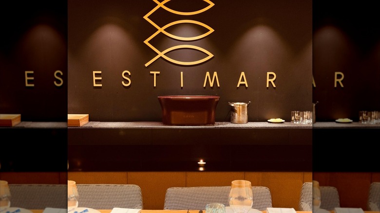 A modern set table with the restaurant logo on a brown wall behind