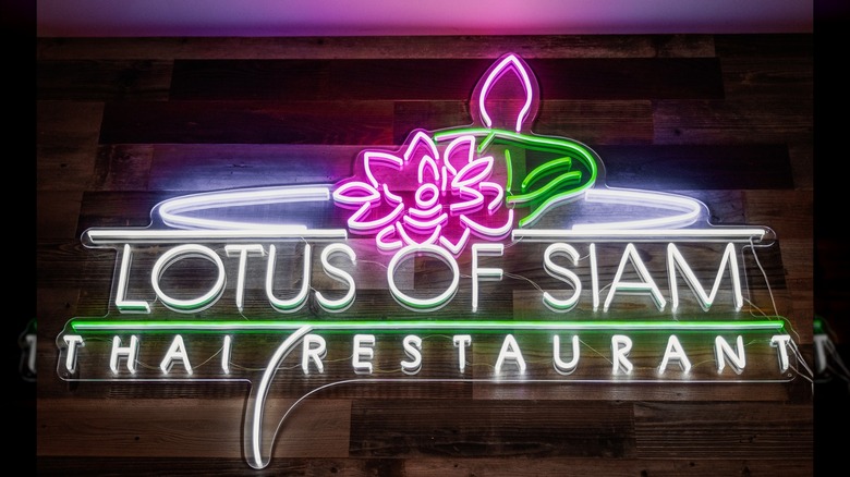 The illuminated sign for Lotus of Siam with a flower above the restaurant name