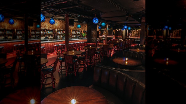 The dark interior of a tiki-themed restaurant with blue buoy lights on the ceiling