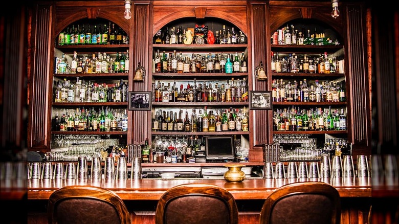 A fully stocked bar with glasses stacked on the bar