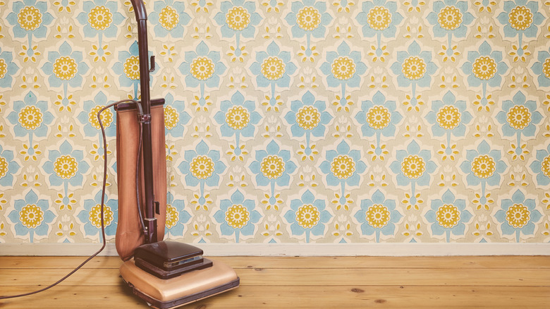 Retro style upbright vacuum against old fashioned wall paper