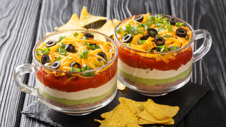 Two glass mugs filled with seven-layer dip