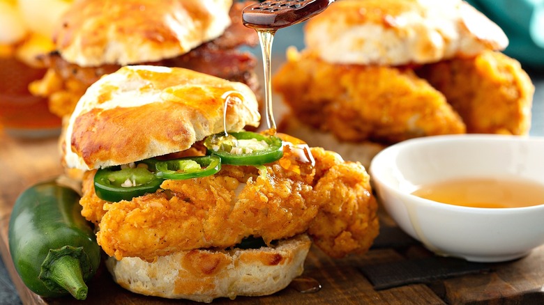 Biscuit with fried chicken, sliced jalapeños, and honey