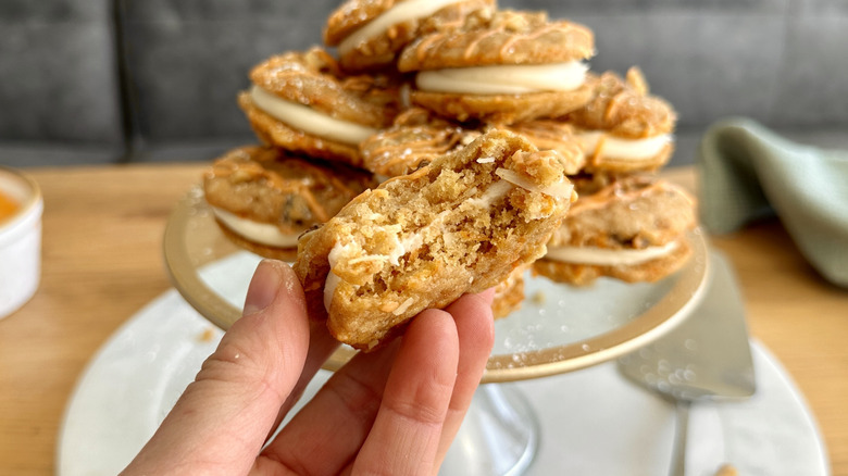 Hand holding carrot cake cookie sandwich with bite taken