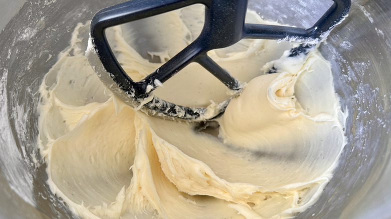 Hand holding cream cheese frosting in piping bag