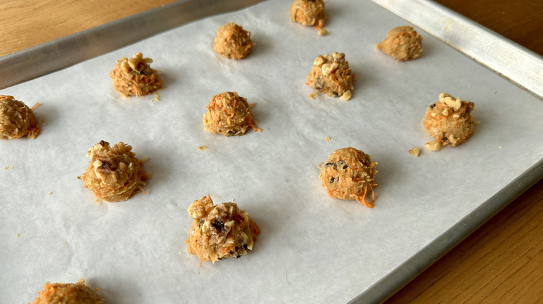 Unbaked walnut-topped carrot cake cookies on baking sheet