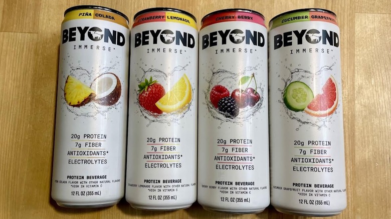Lineup of Beyond Immerse cans lying on a wooden countertop