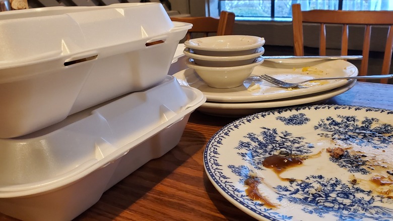Empty plates and carryout containers stacked on table at restaurant
