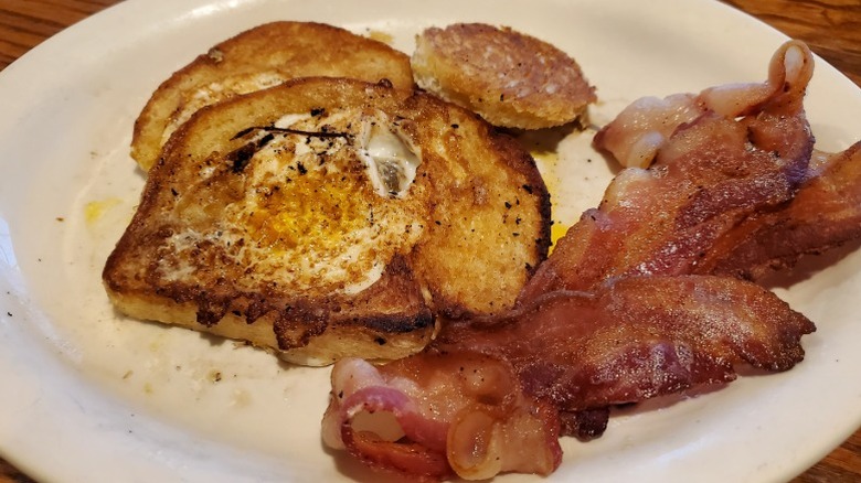Eggs in the basket on a plate with a side of bacon at Cracker Barrel