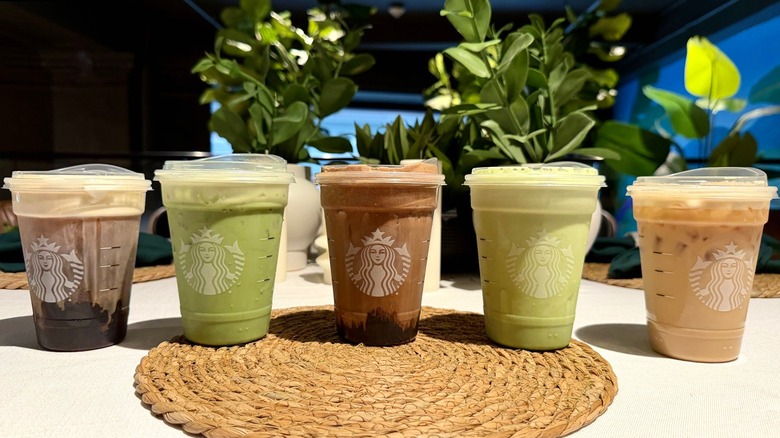 A lineup of 5 new Starbucks protein drinks, with a plain cold foam with cold brew, vanilla protein latte, protein matcha latte, chocolate cold foam, and matcha cold foam
