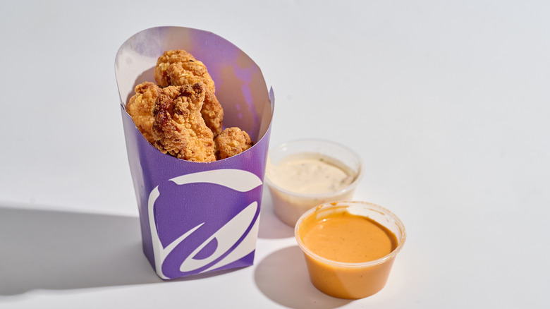 Chicken strips on a table with ranch and hot sauce