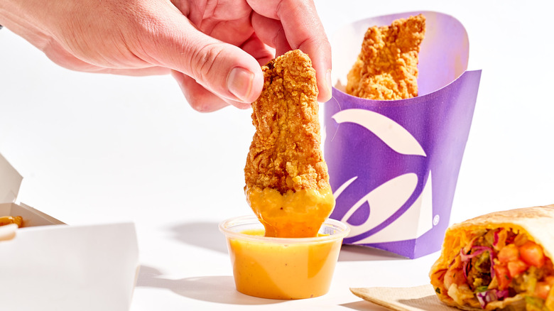 Dipping Taco Bell chicken strip into hot sauce