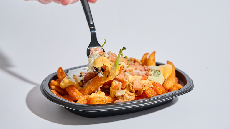Forkful of chicken bacon ranch nacho fries lifting out of a bowl.