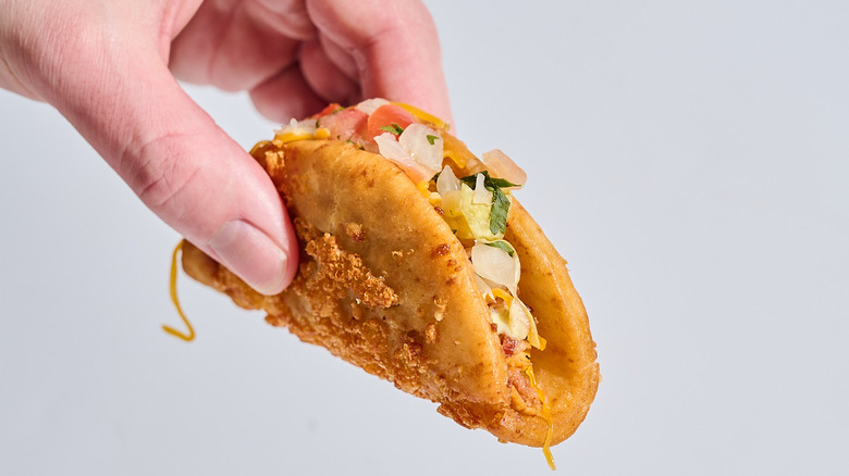 Hand holding a chicken bacon ranch Street Chalupa in the air.