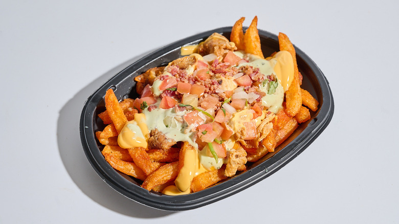 Chicken bacon ranch nacho fries in a container on a table.
