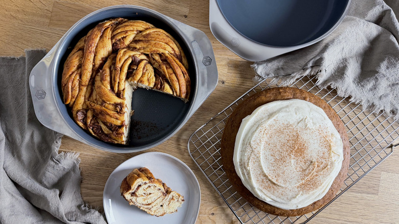 Apple cinnamon babka in a cake pan and a pumpkin cake with cream cheese frosting on a cooling rack